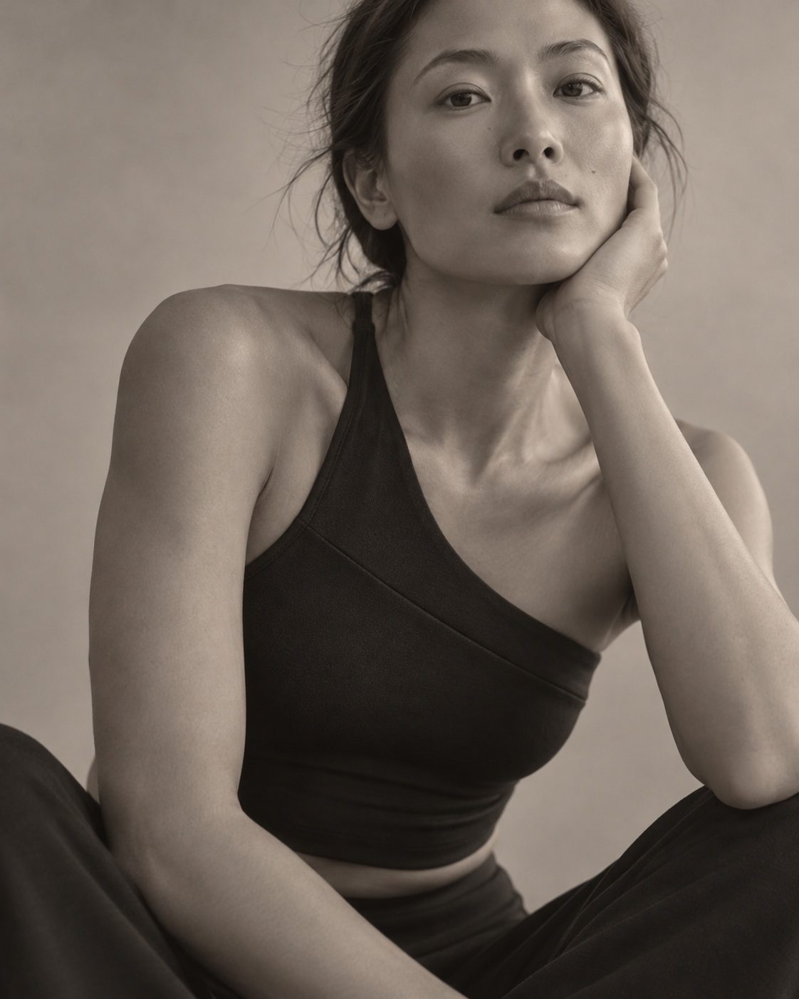 Close portrait of a model in a black activewear top, resting her face on her hand.